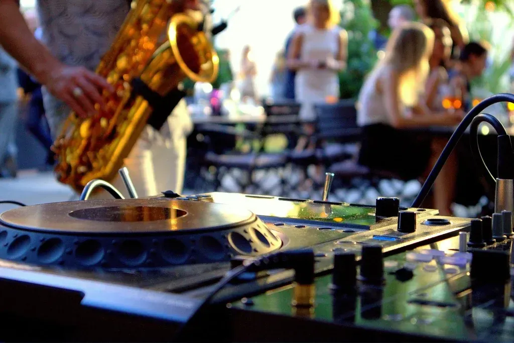 DJ-controller op de voorgrond met saxofonist spelend op de achtergrond